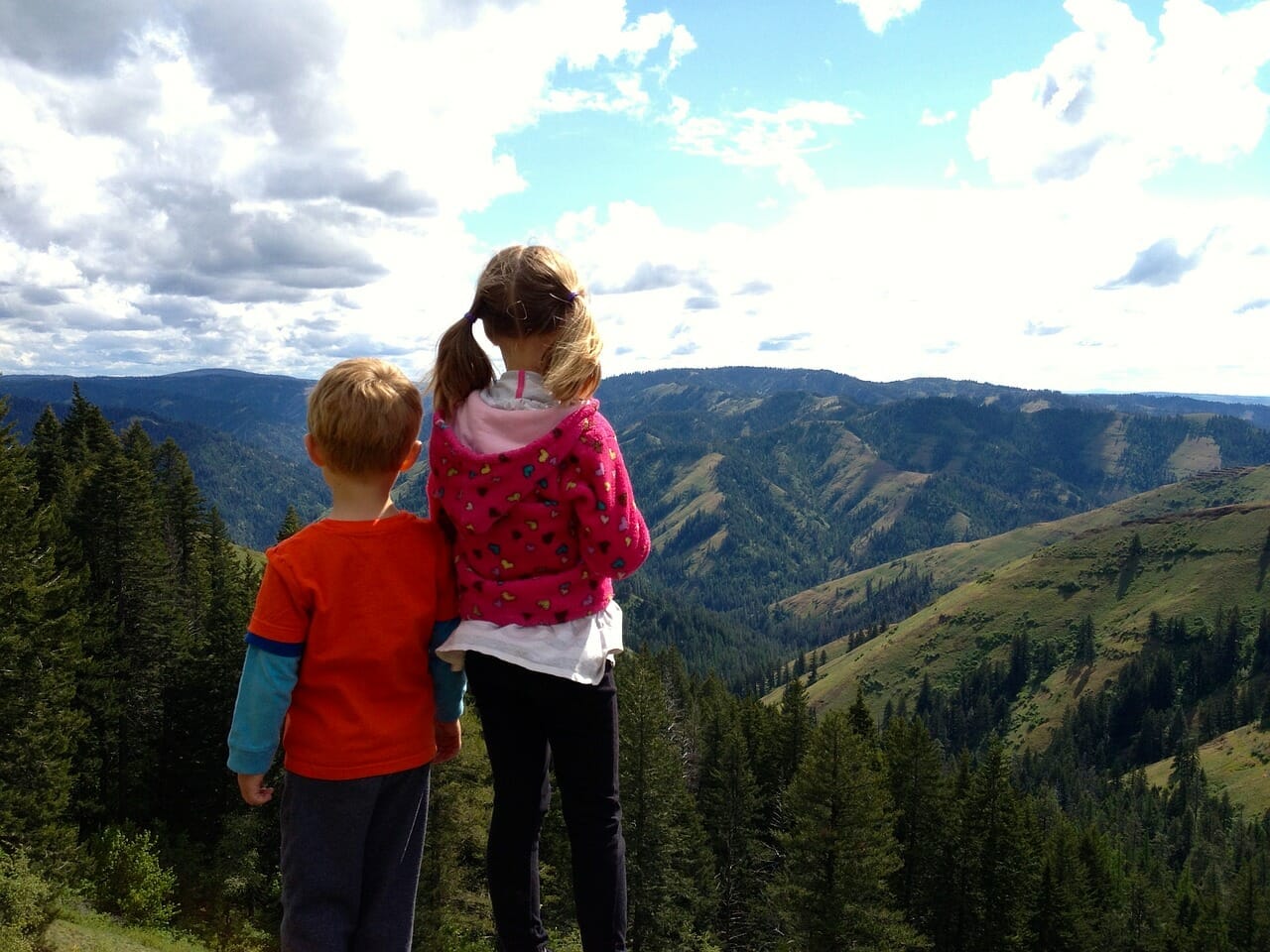 Dve deti stojace na kopci výhľadom do doliny