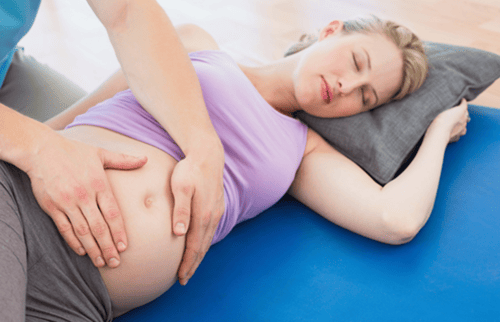 Tehotnú ženu masíruje fyzioterapeut.